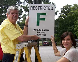 Buddy Lambert and April Saunders, director of creative services for University Communications and Marketing, install the new parking signs.
